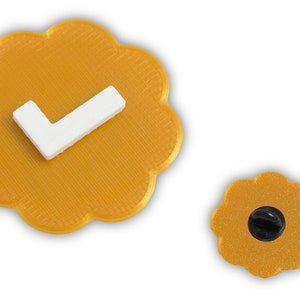 May include: A gold-colored pin shaped like a flower with a white checkmark. The pin has a textured surface and a black pin back. A smaller version of the pin is also shown.