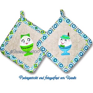 May include: Two green and blue quilted pot holders with a whimsical egg design. Each egg has a smiling face, a bow tie, and a hat. The text "@Stichezauber2017" is on one pot holder. The text "Probegestickt und fotografiert von Ursula" is below the pot holders.