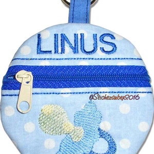 May include: A blue and white fabric zippered pouch with a white polka dot pattern. The pouch has a blue embroidered pacifier design and the name "LINUS" embroidered on the top. The pouch has a silver key ring attached.
