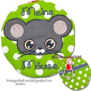 May include: A green fabric coin purse with white polka dots features an embroidered grey mouse with pink ears and large eyes. The purse has a zipper closure and a metal ring. The text "Meine Maus" is embroidered on the front of the purse.