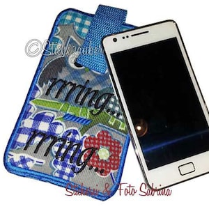 May include: A blue and white patterned phone case with the word "morning" embroidered on it. A white smartphone with a black screen is next to the case.