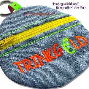Könnte beinhalten: Eine kleine blaue Jeans-Münzbörse mit einem gelben Reißverschluss und dem Wort "TRINKGELD" in orange und grün gestickt. Die Börse hat einen Schlüsselring.