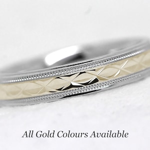 Pode incluir: Uma alian&ccedil;a de dois tons com um padr&atilde;o de diamante no centro. A banda &eacute; feita de ouro branco e amarelo. "Todas as cores de ouro dispon&iacute;veis" est&aacute; escrito abaixo da banda.