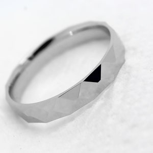 May include: A silver ring with a geometric, faceted design. The ring is made of a smooth, polished metal.