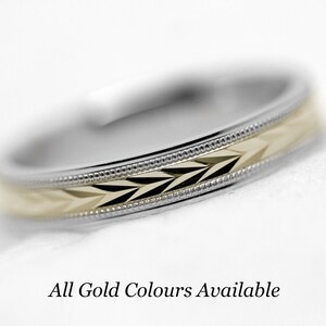 May include: A close-up of a wedding band with a gold and silver design. The band has a textured pattern and a beveled edge. All gold colors are available.
