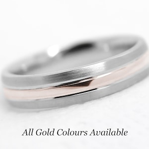 May include: A silver wedding band with a thin rose gold band inset into the center.