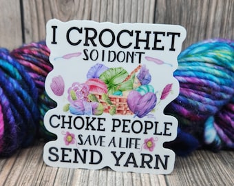 May include: A white sticker with the text "I CROCHET SO I DON'T CHOKE PEOPLE SAVE A LIFE SEND YARN" and a watercolor illustration of yarn balls in a basket. Colorful yarn skeins are in the background.