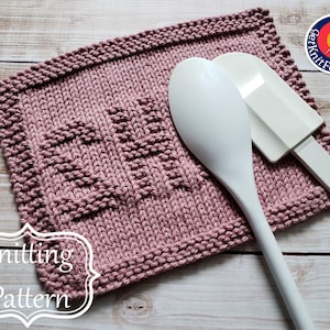 May include: A pink knitted dishcloth with a textured pattern. The dishcloth is laying on a wooden surface with two white kitchen utensils on top of it. The text "Knitting Pattern" is on a white label in the lower left corner of the image.