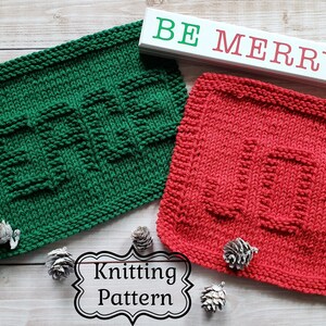May include: Two knitted dishcloths, one green with the word "Peace" and one red with the word "Joy". The dishcloths are on a wooden surface with the words "Be Merry" on a white sign.