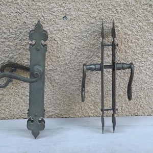 May include: Two antique door handles with ornate designs. The handle on the left has a curved lever and a decorative finial. The handle on the right has a straight lever and a pointed finial.