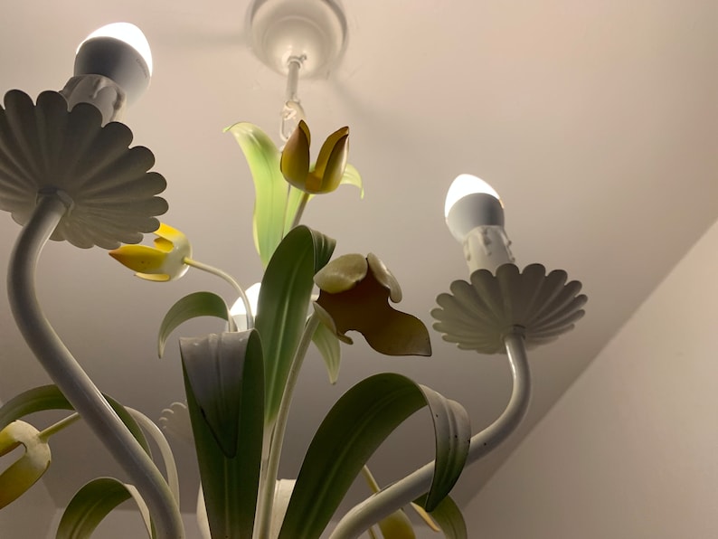 K&ouml;nnte beinhalten: Wei&szlig;e Metall-Luster mit floralem Design. Der Kronleuchter hat f&uuml;nf Lichter und verf&uuml;gt &uuml;ber gelbe und gr&uuml;ne Tulpen.