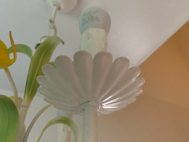 K&ouml;nnte beinhalten: Wei&szlig;er Metall-Kronleuchter mit floralem Design. Der Kronleuchter hat eine wei&szlig;e Gl&uuml;hbirne und eine wei&szlig;e Deckenbefestigung.