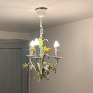 K&ouml;nnte beinhalten: Wei&szlig;er Metall-Kronleuchter mit gelben und gr&uuml;nen floralen Akzenten und vier Gl&uuml;hbirnen.