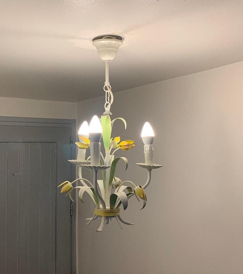 K&ouml;nnte beinhalten: Wei&szlig;er Metall-Kronleuchter mit gelben und gr&uuml;nen floralen Akzenten und vier Gl&uuml;hbirnen.