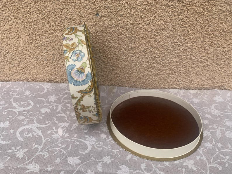 May include: Two round, floral patterned boxes. One box is closed and the other is open, revealing a brown interior.