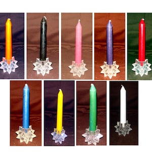May include: Ten candles of different colors, each on a clear glass star-shaped candle holder. The colors are orange, black, pink, purple, red, blue, yellow, green, white, and brown.