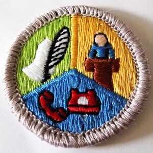 May include: Embroidered patch with a circular design. The patch is divided into four sections: green with a white feather, yellow with a figure behind a podium, blue with a red telephone, and a gray border.
