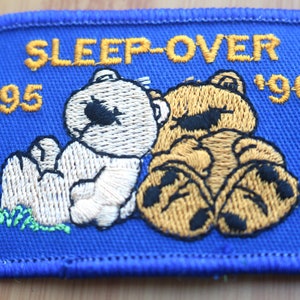May include: A blue embroidered patch with two teddy bears, one white and one brown, with the text "SLEEP-OVER '95 '96".