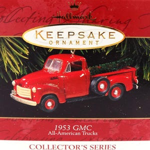 May include: A red 1953 GMC pickup truck ornament with a Christmas tree in the truck bed. The ornament is part of the Hallmark Keepsake Collector's Series. The truck has black tires and a spare tire on the side.