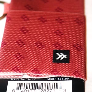 May include: A red wallet with a repeating geometric pattern. The wallet has a black square with a white arrow design. The tag reads "Made in China".