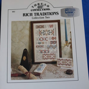 May include: A cross stitch pattern booklet titled "Rich Traditions Collection Two" by Thread Connections. The cover features a framed cross stitch design with a variety of geometric patterns in red, blue, and white. The design is surrounded by a brown frame and a white background.