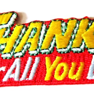May include: Embroidered patch with the words "THANKS" in yellow, outlined in white and green, above "FOR ALL YOU DO" in white and yellow. The patch has a red background.