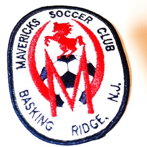 May include: White and blue embroidered patch with a red soccer ball and a red horse. The text reads "Mavricks Soccer Club, Basking Ridge, NJ".