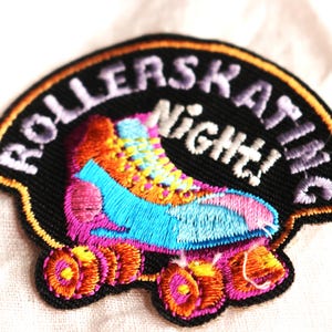 May include: A black and orange embroidered patch with the text "Roller Skating Night!" and a colorful roller skate with pink, blue, yellow, and orange details.