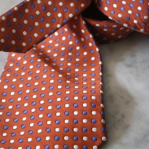 May include: A brown silk tie with white and blue polka dots.