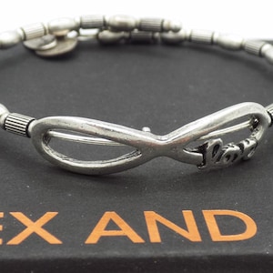 May include: Silver-toned bracelet featuring an infinity symbol with the word "Love" and a beaded design. The bracelet is displayed on a black box with the brand name "ALEX AND ANI" in orange lettering.