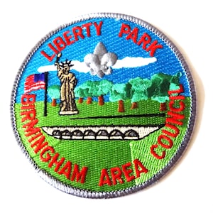 May include: Embroidered patch with a circular design. The patch features the Statue of Liberty, a bridge, trees, and a flag. Text includes "Liberty Park Council" and "Birmingham Area". The patch has a blue, green, and red color scheme.