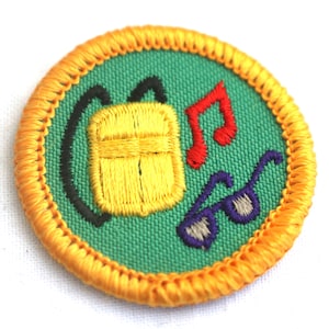 May include: A green and yellow embroidered scout badge with a yellow backpack, red musical notes, and purple sunglasses.