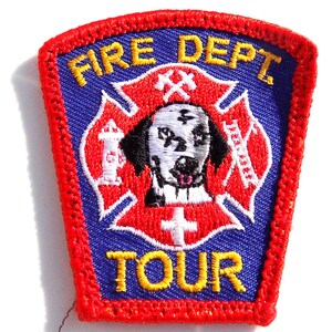 May include: A rectangular patch with a red border and a blue center. The patch features the words "FIRE DEPT TOUR" in yellow. A Dalmatian dog is in the center of a red Maltese cross design. A fire hydrant and ladder are also visible.
