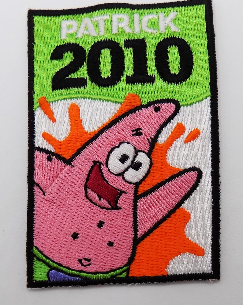 May include: Embroidered patch featuring Patrick Star from Spongebob Squarepants. The patch has a pink starfish design with a smiling face, set against an orange and white background. The text "PATRICK 2010" is displayed at the top in white and black.