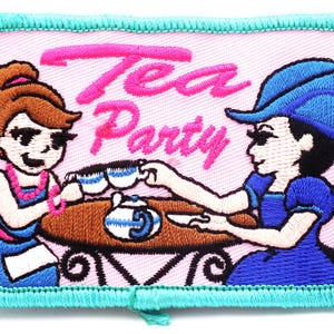 May include: Embroidered patch with a pink background and a teal border. The patch features two cartoon women at a table with teacups and a teapot. The words "Tea Party" are embroidered in pink.