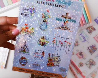May include: A sheet of clear stickers with a blue background and white stars. The stickers feature various religious quotes and images, including a cross, a church, flowers, and a guitar. The text on the stickers includes "Grow in Grace", "God is Good", "God says you are", and "The Lord is my strength and my song".