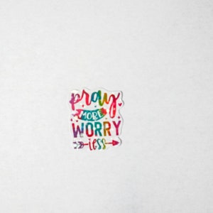 May include: A colorful sticker with the text "pray more worry less" in a rainbow font with an arrow pointing to the right.