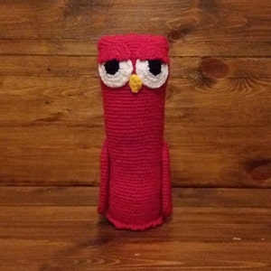 Może przedstawiać: Hakowana zatyczka do butelki w kształcie sowy w jasnoróżowym kolorze z białymi oczami i żółtym dziobem.