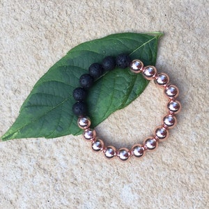 May include: A bracelet with black lava beads and rose gold beads.