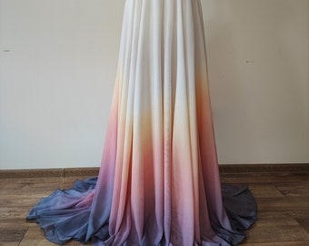 May include: A long white chiffon skirt with a gradient ombre design. The skirt transitions from white at the top to a light yellow, then orange, pink, and finally a deep purple at the bottom.