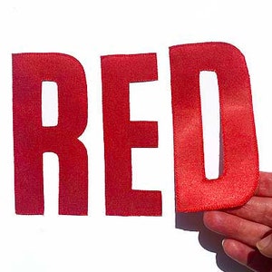Op de afbeelding: Rode viltletters die het woord "ROOD" spellen.