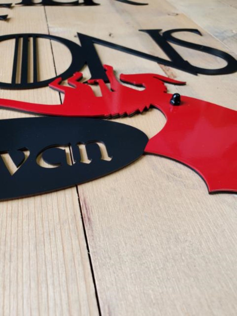 May include: Black and red metal wall decor with the words "Stark" and "House Stark" and a dragon design.