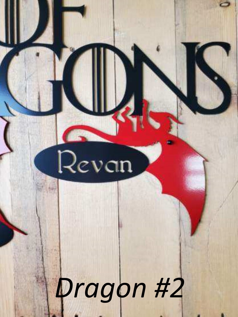 May include: A red metal dragon with a black oval sign that says "Revan" underneath. The dragon is attached to a wooden wall with the words "Game of Thrones" in black metal letters above it. The text "Dragon #2" is written below the dragon.