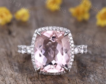 Könnte beinhalten: Ein Kissen-geschliffener rosafarbener Morganit-Verlobungsring mit einem Heiligenschein aus kleineren Diamanten. Der Ring ist in einer Weißgold-Schiene mit einer Pavé-Diamant-Fassung gefasst.
