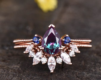 Anillo de compromiso vintage de alejandrita en oro rosa con corona de moissanita y zafiro.