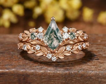 Conjunto de anillo de compromiso de ágata musgosa tallada en cometa y alianza de boda de oro rosa con diseño de hojas y ramas.