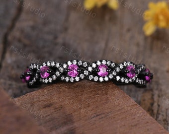 May include: Black and white wedding band with pink gemstones set in a twisted design.