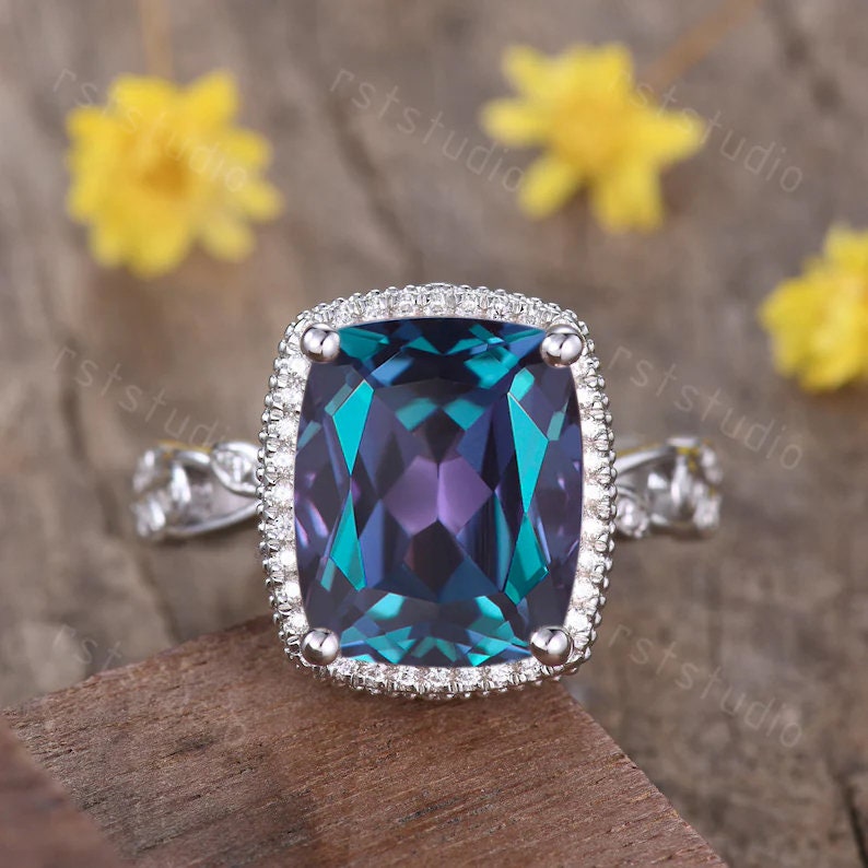 May include: A silver ring featuring a large, square-shaped, iridescent gemstone encircled by a halo of smaller diamonds. The gemstone displays a deep blue, green, and purple hue.