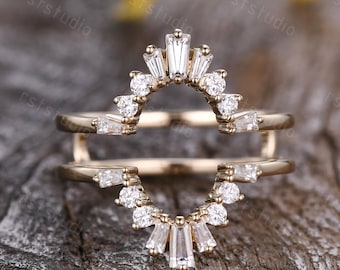 May include: A gold ring with a delicate, curved design featuring a row of small round diamonds and a row of baguette diamonds. The ring is designed to be worn as a wedding band or a promise ring.