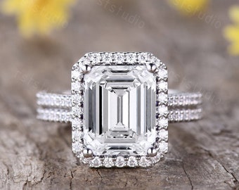 Anillo de moissanita de talla esmeralda con halo de diamantes en oro blanco y alianza de boda.